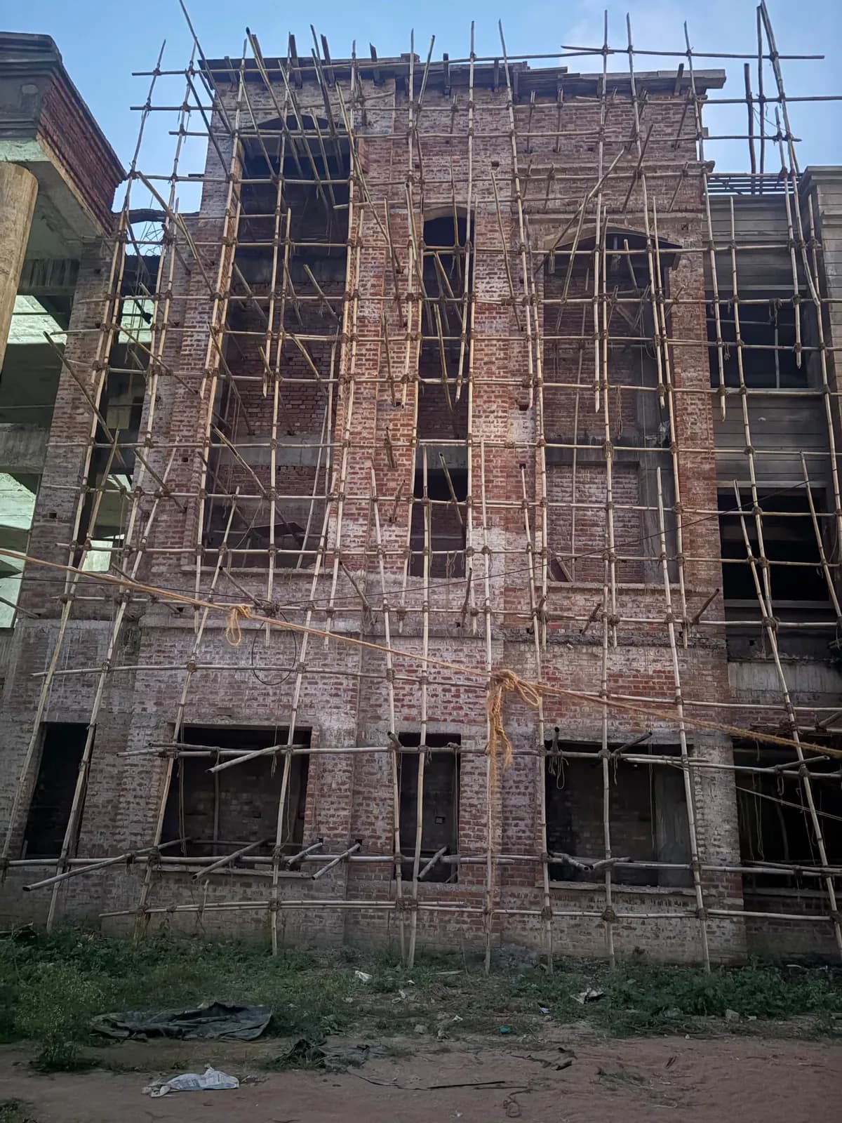 Brick façade with tall arched window openings under scaffolding
