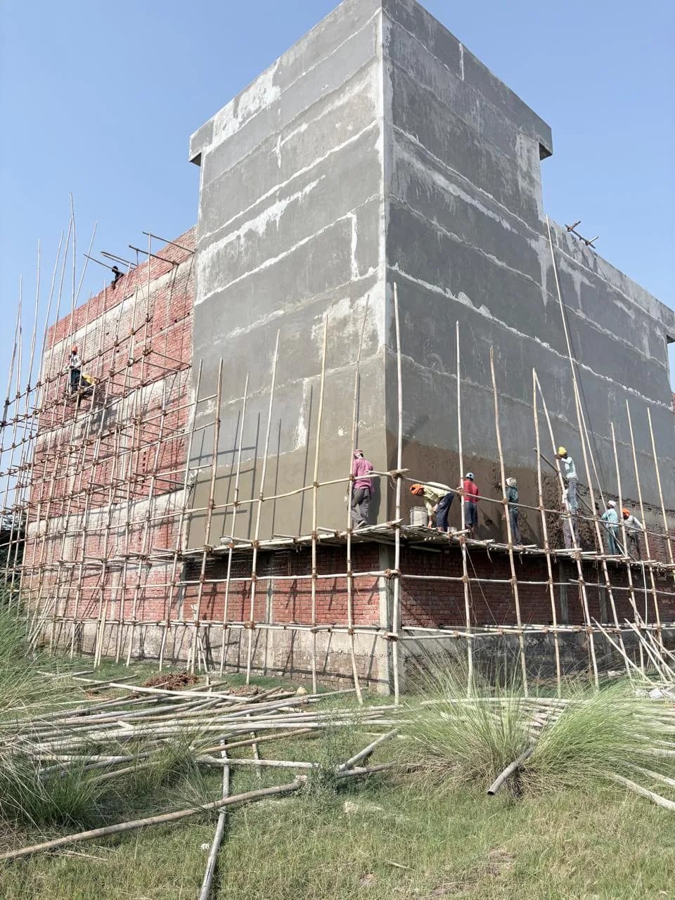 Plastering in progress with workers on scaffolding